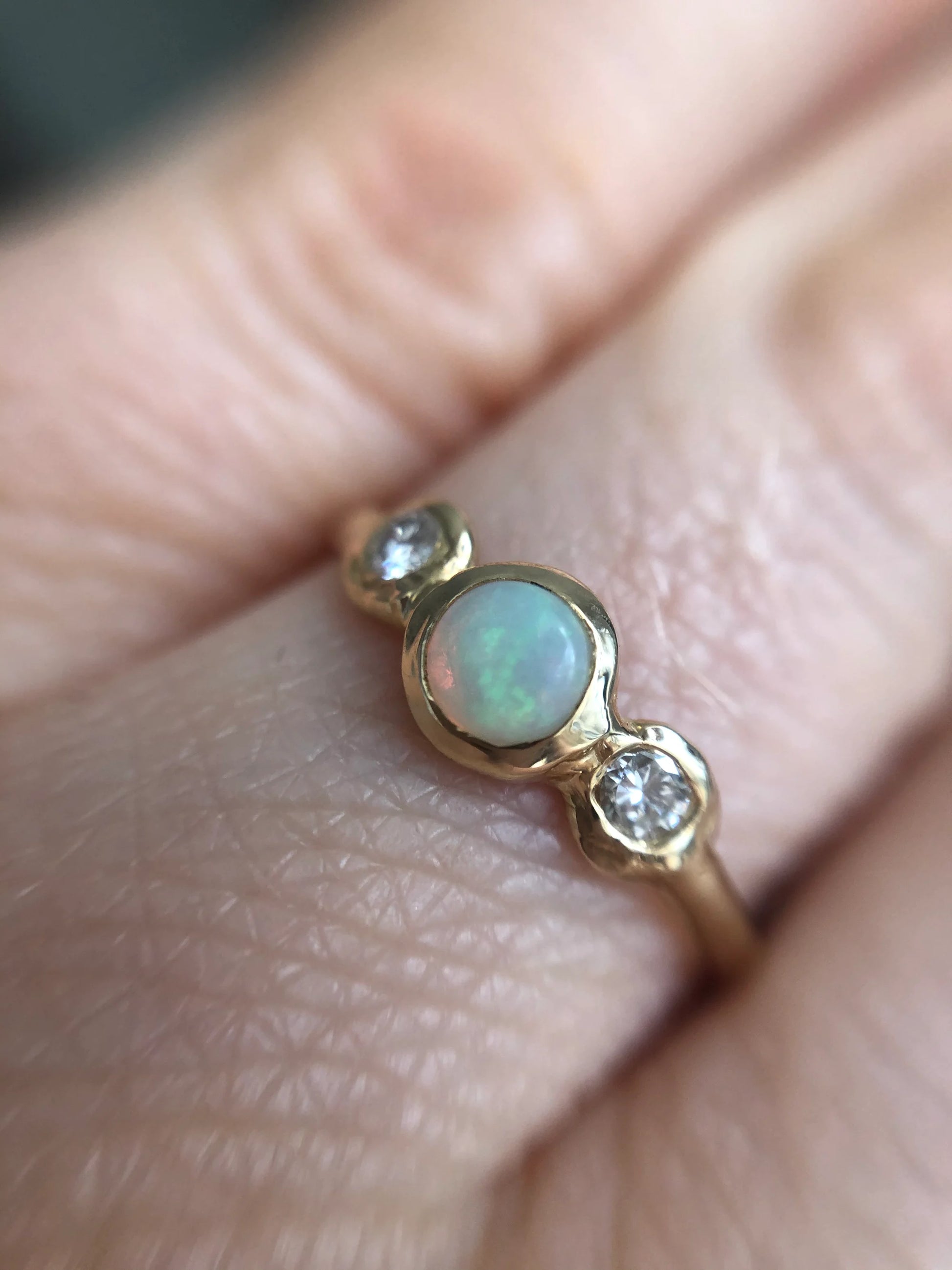 Gold ring with an opal and diamonds on a finger