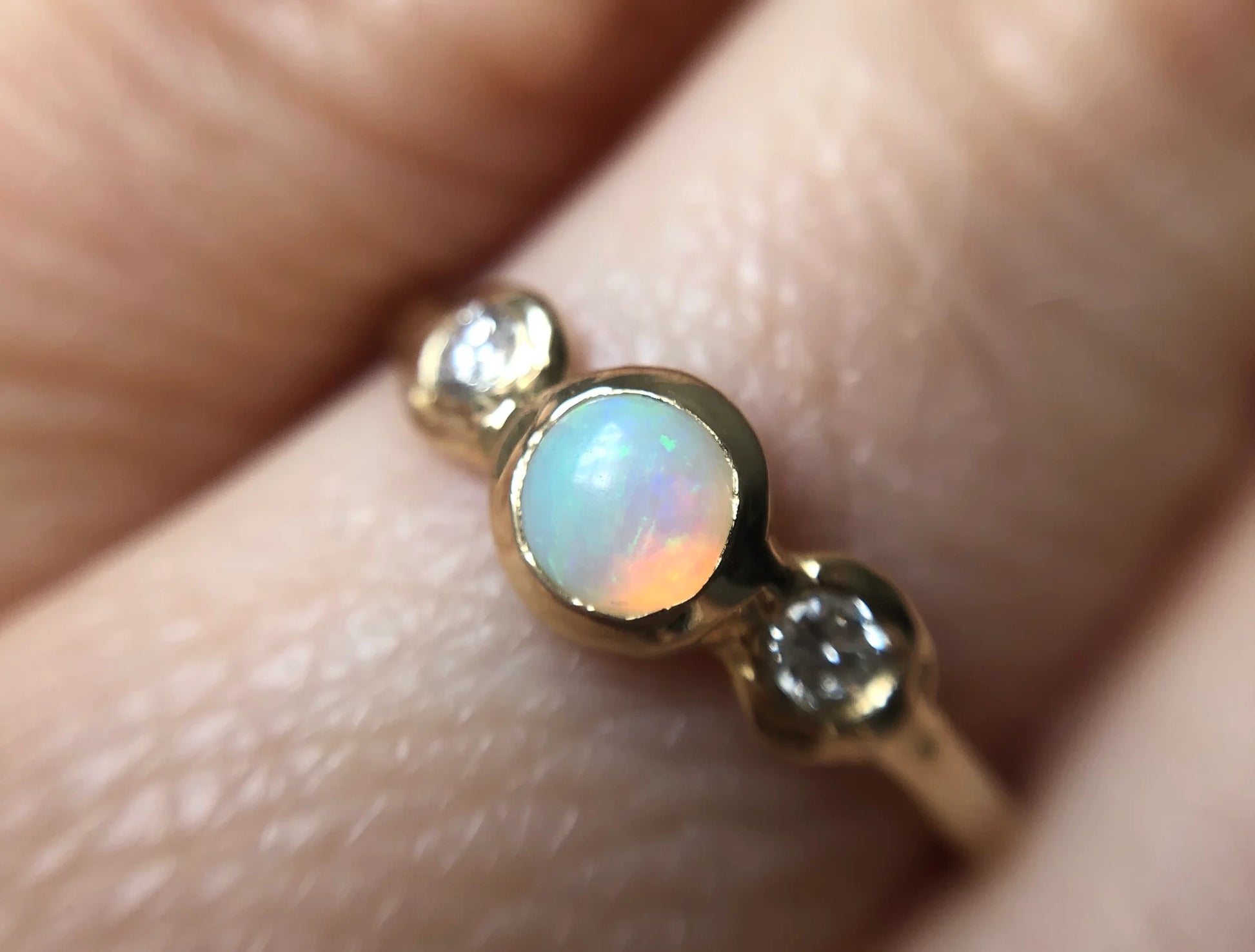 Gold ring with an opal stone on a finger