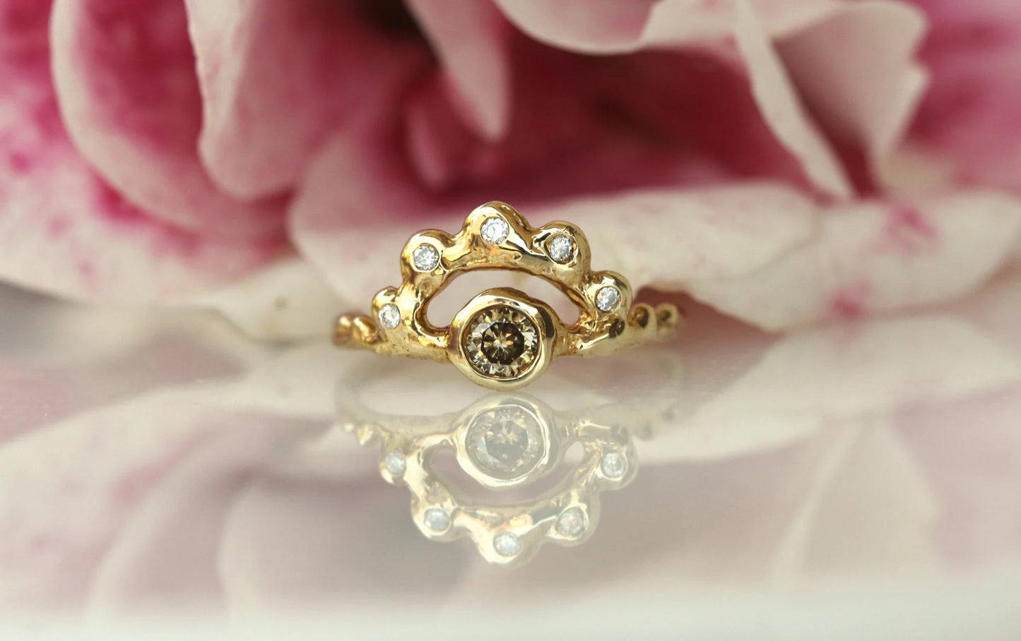 Gold ring with a central gemstone on a pink floral background