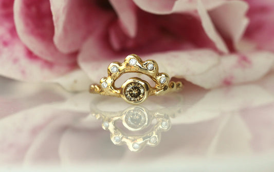 Gold ring with a central gemstone on a pink floral background