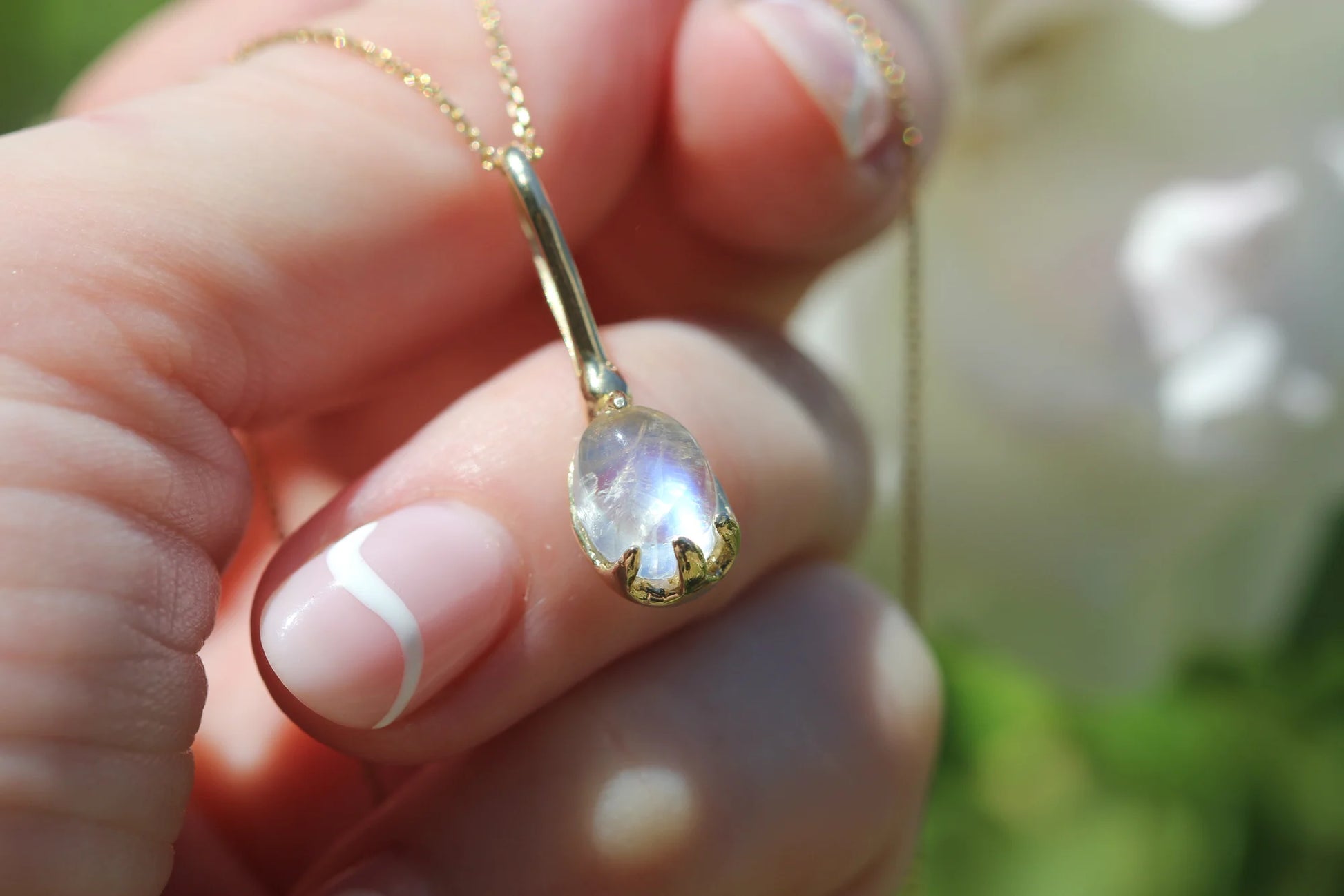 Gold necklace with a pendant held by a hand against a blurred background